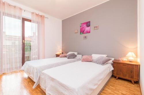 Duas camas num quarto branco com uma janela em Apartments Rede em Pula