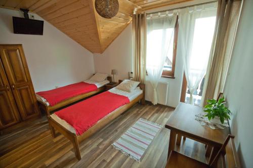 una camera con due letti, un tavolo e una finestra di Pokoje u Danusi a Szczawnica