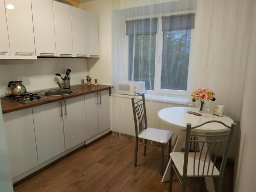 カリーニングラードにあるАпартаменты в ЦЕНТРЕ у ОЗЕРАの白いキャビネット、テーブルと椅子付きのキッチンが備わります。