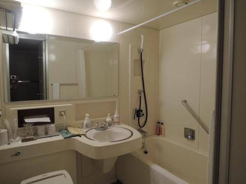uma casa de banho com um lavatório, um espelho e uma banheira em KKR Kyoto Kuniso em Quioto