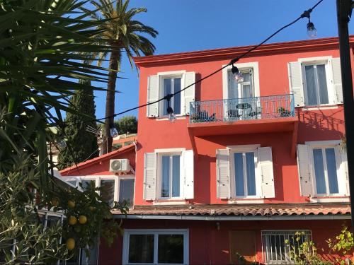 a red building with white windows and a palm tree at Hôtel La Villa Patricia - Charme et Tradition in Villefranche-sur-Mer