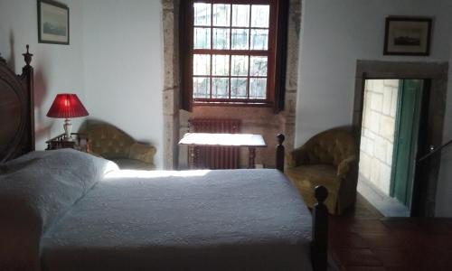 a bedroom with a bed and a chair and a window at Quarto das Lamparinas in Ponte de Lima