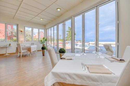 a dining room with a large white table and windows at Hotel Villa Garuti in Padenghe sul Garda