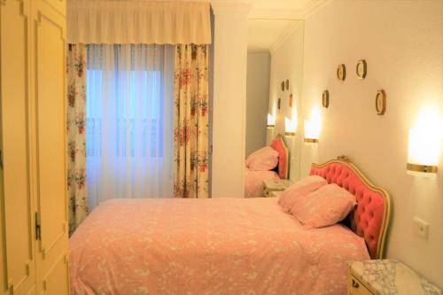 a bedroom with a bed with pink sheets and a window at Casa Plaza Sierra Grazalema in Grazalema