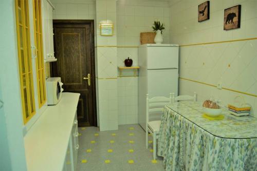 a kitchen with a table and a refrigerator at Casa Plaza Sierra Grazalema in Grazalema
