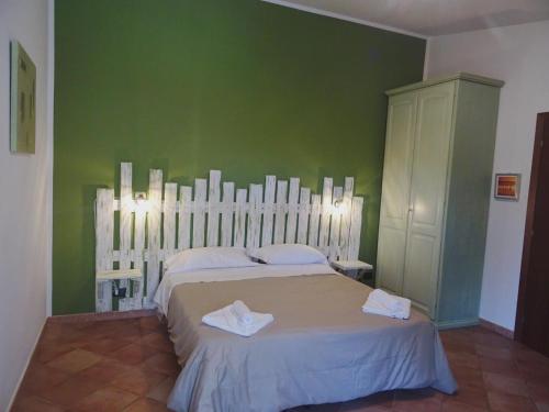 a bedroom with a large bed with a green wall at Clock's House in Fiumicino