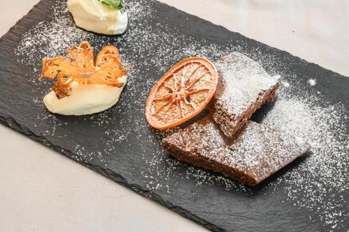 a black plate with bread and a slice of orange at Hotel Villa Garuti in Padenghe sul Garda