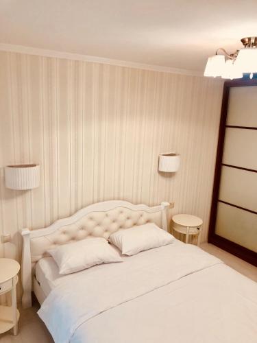 a bedroom with a white bed with two tables at Classic Apartment in Boryspilʼ