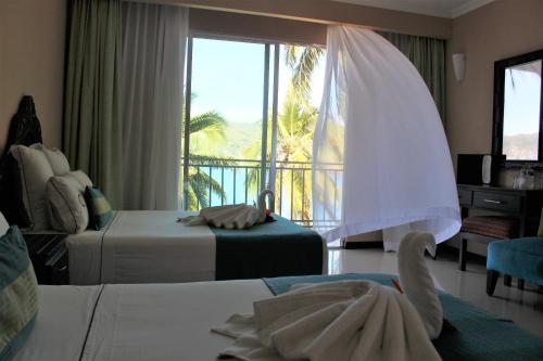 a hotel room with two beds and a large window at La Quinta Gran Bahía, Cuastecomates - Todo Incluido in Cuastecomate