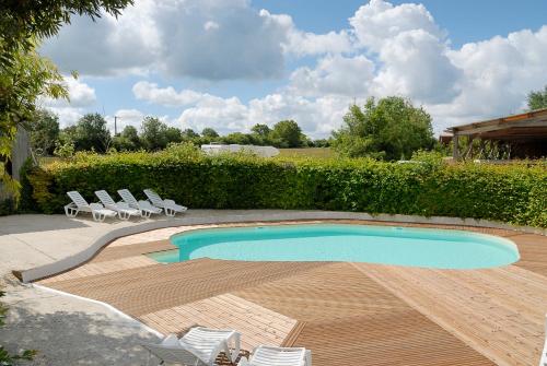une piscine avec des chaises et une terrasse en bois dans l'établissement La Ferme du Marais Poitevin - Roulotte, à Benet