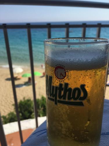 a glass of beer sitting on a table next to the beach at Regina Apartments in Lassi