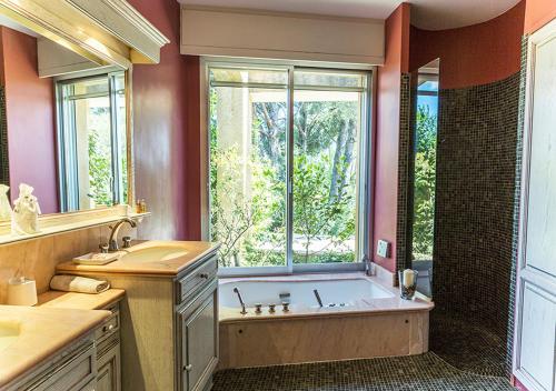 a large bathroom with a tub and a window at Au Coeur des Vignes en Provence in Châteauneuf-de-Gadagne