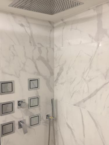 a bathroom with a shower with white marble walls at Porto Enetiko Suites in Rethymno Town