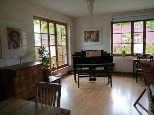 ein Wohnzimmer mit einem Klavier, einem Tisch und Fenstern in der Unterkunft Haus Vincent Stralsund in Stralsund