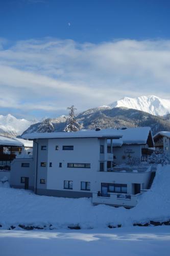 a building in the snow with mountains in the background at Haus Helvetia in Ladis