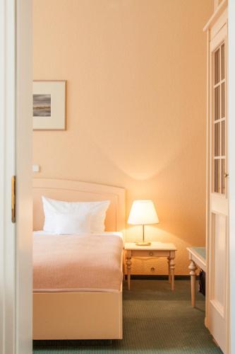 a bedroom with a bed and a table with a lamp at Hotel Villa Auguste Viktoria in Ahlbeck