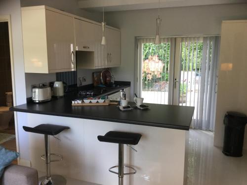 a kitchen with a black counter and two stools at Plas Y Dderwen Apartments in Aberystwyth