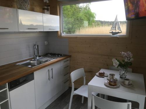 una pequeña cocina con mesa y un velero en la ventana en Houseboat Ślesin, en Ślesin
