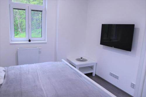 a white bedroom with a bed and a tv on the wall at JM Apartments in Hardegg