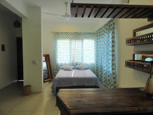 a bedroom with a bed and a window and a bench at Paziflora Hostel in Puerto Escondido