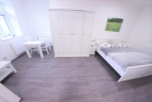 a white bedroom with a bed and a table at JM Apartments in Hardegg