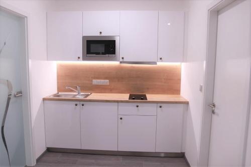 a kitchen with white cabinets and a sink and a microwave at JM Apartments in Hardegg