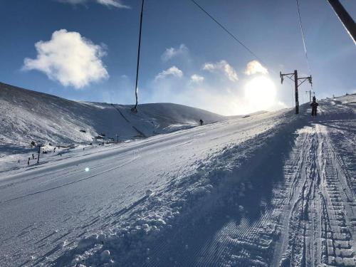 a person riding a ski lift on a snow covered slope at Stelvio in Aviemore