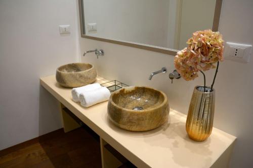 a bathroom with two sinks and a vase with flowers at Le Nicchie luxury rooms in Lecce