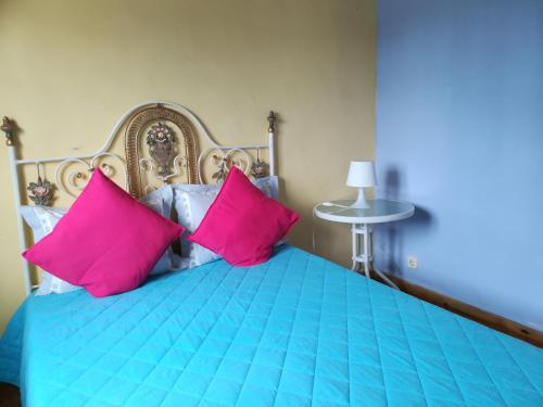 ein Schlafzimmer mit einem blauen Bett und rosa Kissen in der Unterkunft Casa Azul in Nazaré