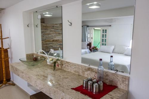 a bathroom with a sink and a bed and a mirror at Pousada Paraiso do Alto in Paraisópolis