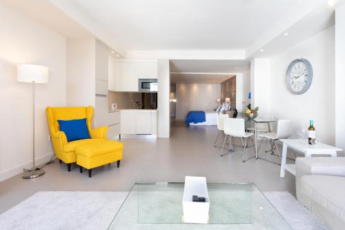 ein Wohnzimmer mit einem gelben Stuhl und einer Couch in der Unterkunft Rooms & Suites Loft 2H Deluxe Edition Arrecife in Arrecife