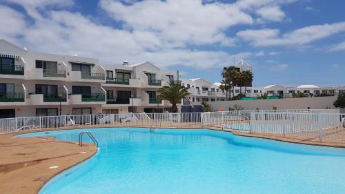 une grande piscine en face d'un bâtiment dans l'établissement Lanzarote-Beach-Apartment, Las Cucharas Beach, Costa Teguise -- 1 MINUTE WALK FROM MAIN SQUARE, 35 METERS FROM BEACH, à Costa Teguise