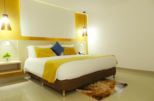 a bedroom with a large bed with yellow and blue pillows at Hotel Tayrona del Mar in Santa Marta