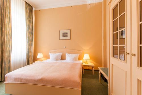 a bedroom with a large bed with two lamps at Hotel Villa Auguste Viktoria in Ahlbeck