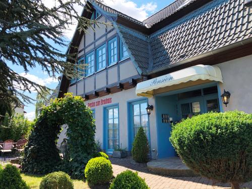 un bâtiment bleu et blanc avec des buissons devant lui dans l'établissement Pension zum Brauhaus, à Stralsund