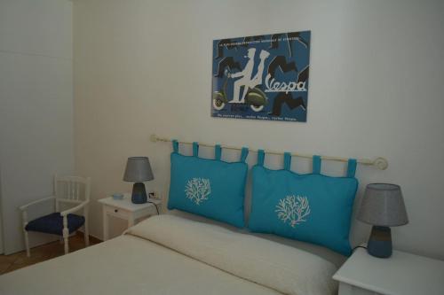 a bedroom with a bed with two blue pillows at Casa della Vespa in Orosei