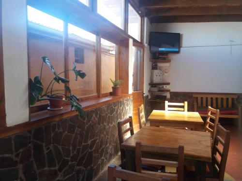 una sala da pranzo con tavolo, sedie e TV di Hostal Nuevo Amanecer a San Pedro de Atacama