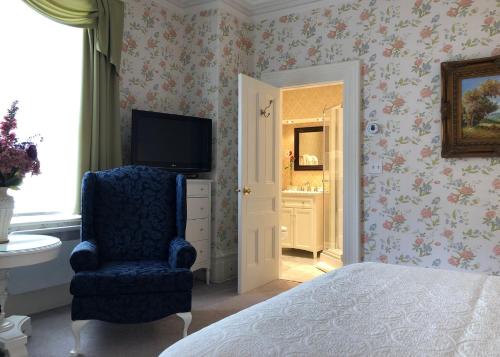 a bedroom with a bed and a chair and a television at Balmoral House Bed & Breakfast in St. John's