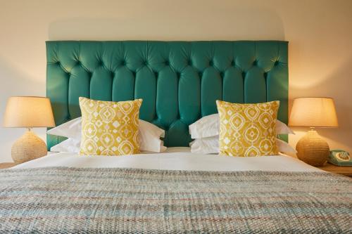 a bedroom with a large bed with a green headboard at The Swan, Streatley, Berkshire in Streatley
