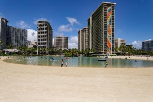 une plage avec des gens dans l'eau et dans les bâtiments dans l'établissement Apartments at Palms Waikiki, à Honolulu