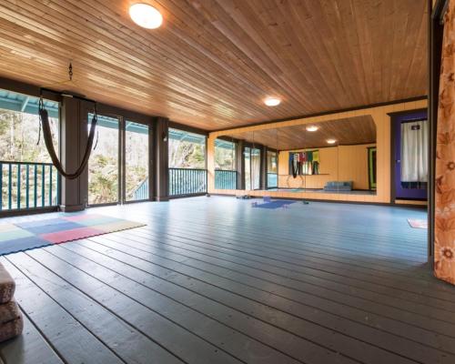 a large room with a wooden floor and windows at Honu Hale in Volcano