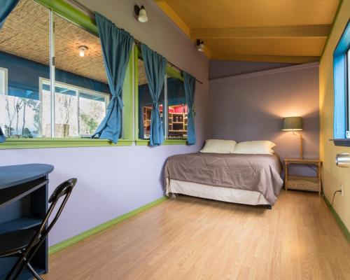 - une chambre avec un lit et quelques fenêtres dans l'établissement Honu Hale, à Volcano
