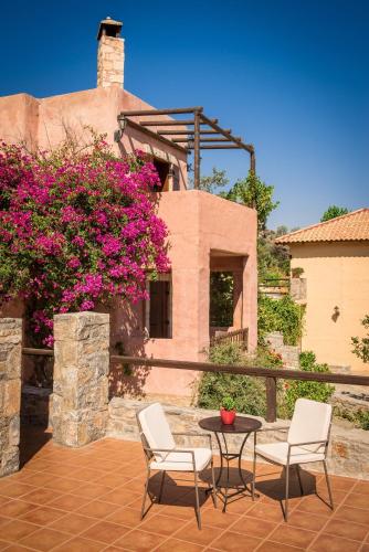 a patio with two chairs and a table and flowers at Enagron Ecotourism Village in Axós