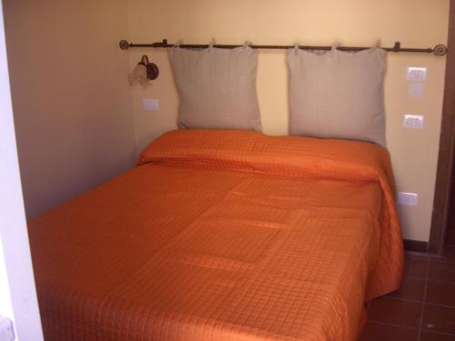 a bed with an orange comforter in a room at Hotel Paese Corvara in Beverino