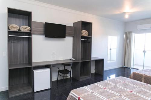 1 dormitorio con 1 cama y escritorio con TV en Hotel Bergozza, en Rio do Sul