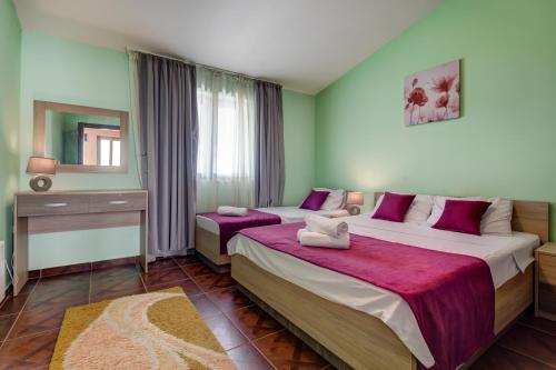 a bedroom with two beds with purple and green walls at Villa Vistamar Lapcici in Budva