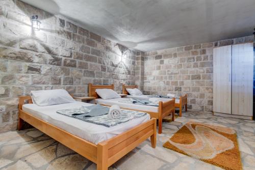 a room with three beds and a brick wall at Villa Vistamar Lapcici in Budva