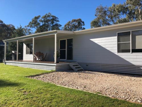 a small white house with a lawn in front of it at Rosewood Cottage Mudgee in Grattai