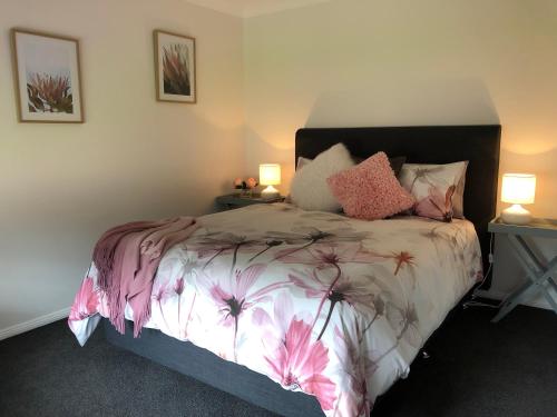 a bedroom with a bed with pink flowers on it at Rosewood Cottage in Grattai