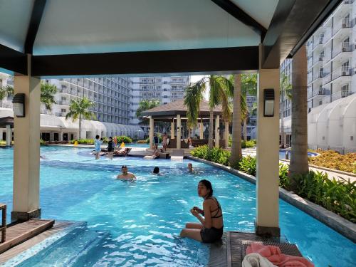 a woman sitting in a swimming pool at a hotel at Shell Residence Manila in Manila